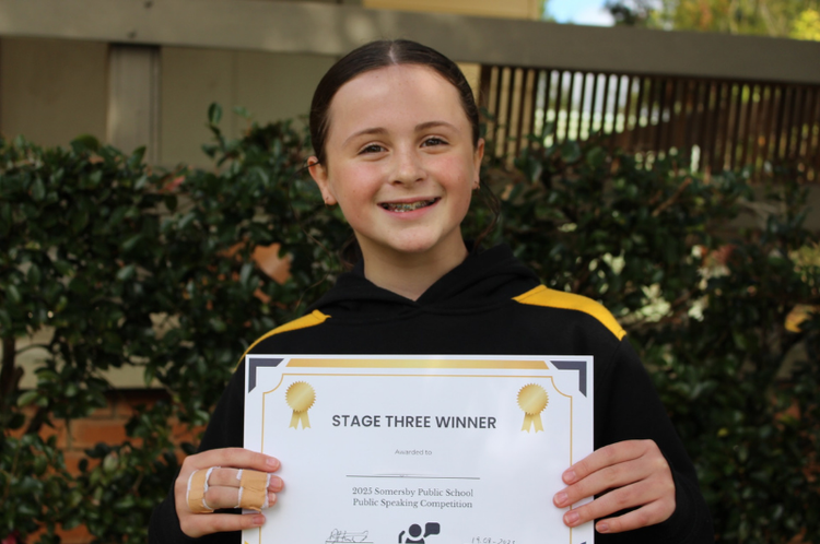 a female student holding up her award for public speaking