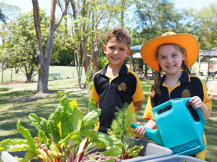 two students watering the vegetable garden