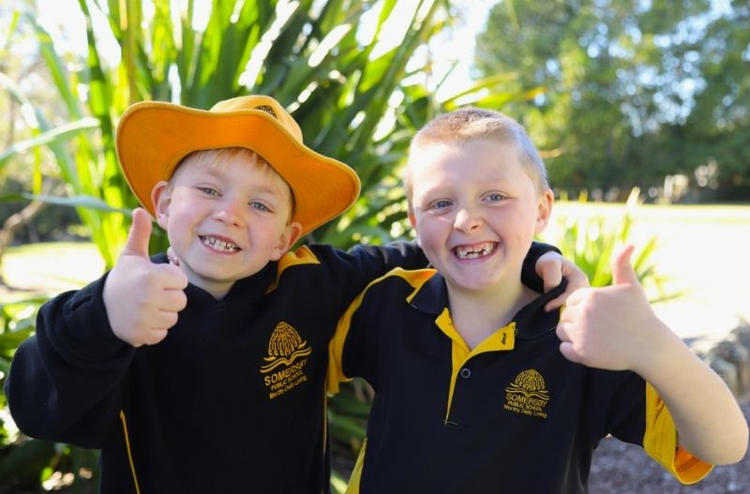 two male students smiling at the camera with their thumbs up