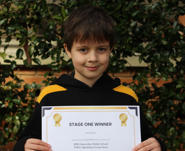 a male student holding an award for public speaking